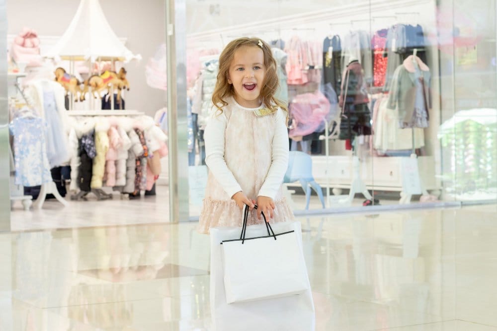 a happy little girl with shopping bags in hands