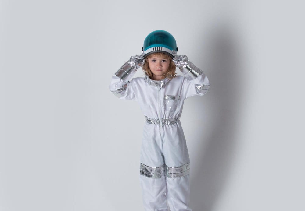Little girl astronaut in space suit holding helmet
