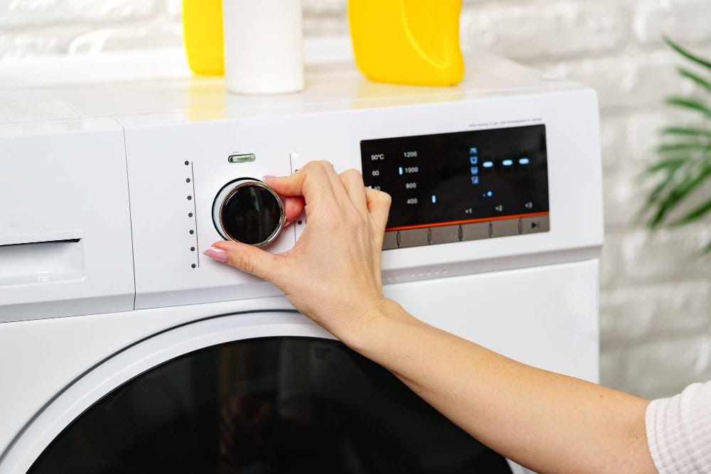 Woman setting a tumble dryer in laundry room