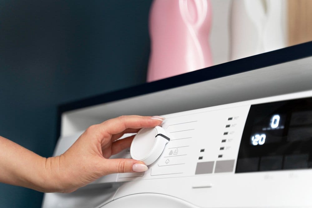 A woman setting a tumble dryer temperature