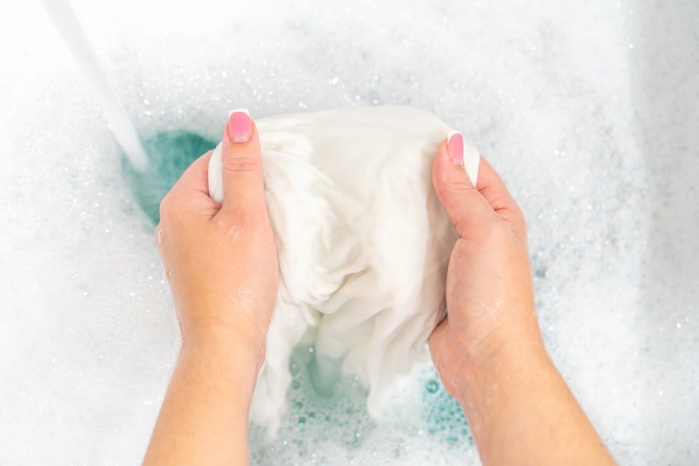 Hand washing baby clothes in sink