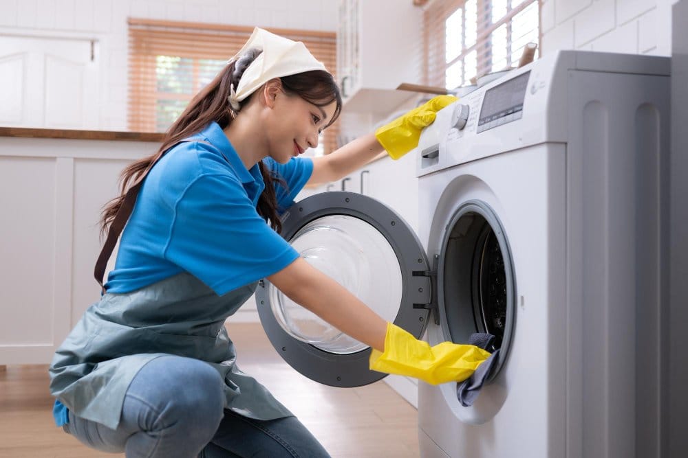 A woman cleaning a washing machine at home