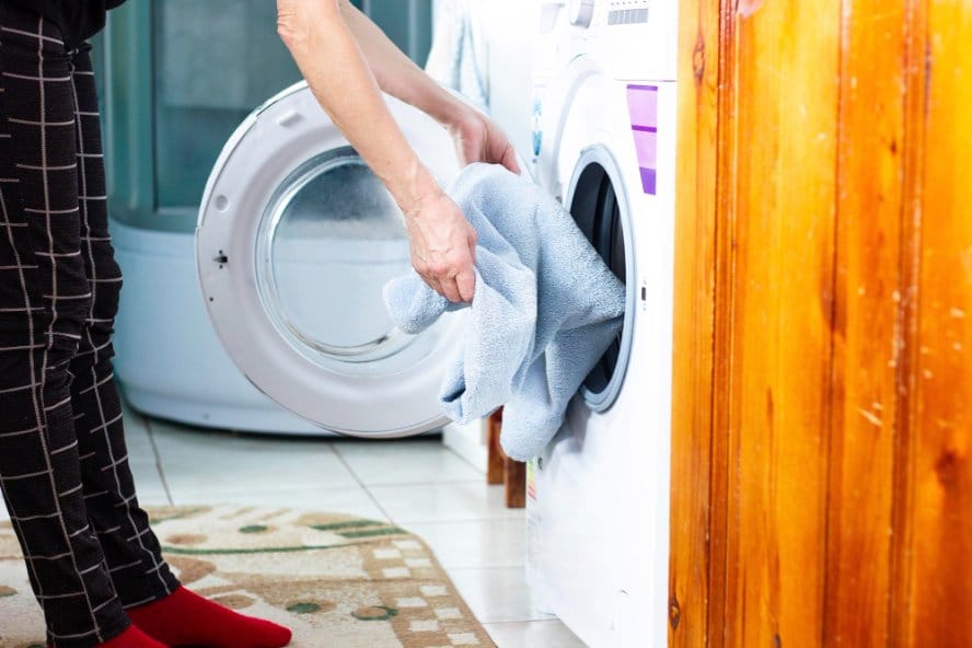 A woman loading baby bedding in a washing machine