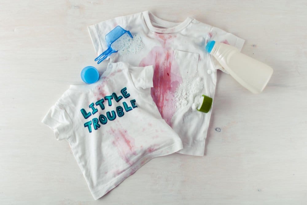 Dirty clothing with red sauce spots and stain remover on top