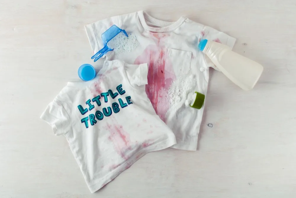 Dirty clothing with red sauce spots and stain remover on top