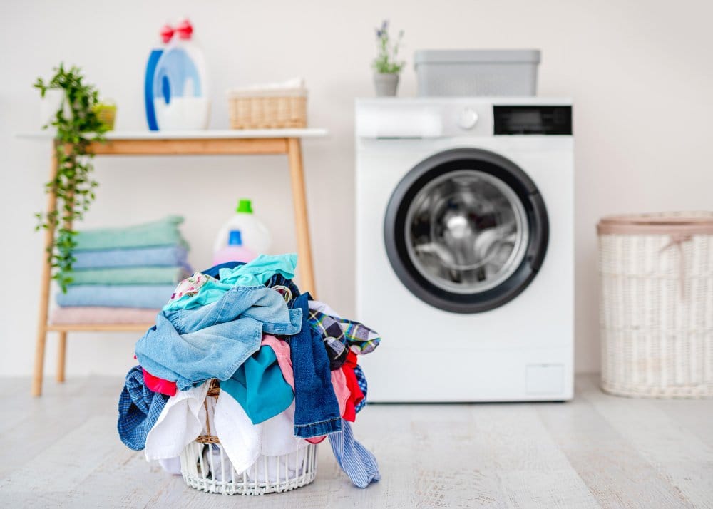 Pile of clothing in a laundry basket near a washing machine