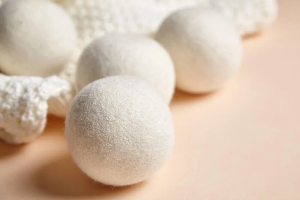 Natural alternatives to dryer sheets including wool dryer balls, vinegar, and baking soda for baby clothes