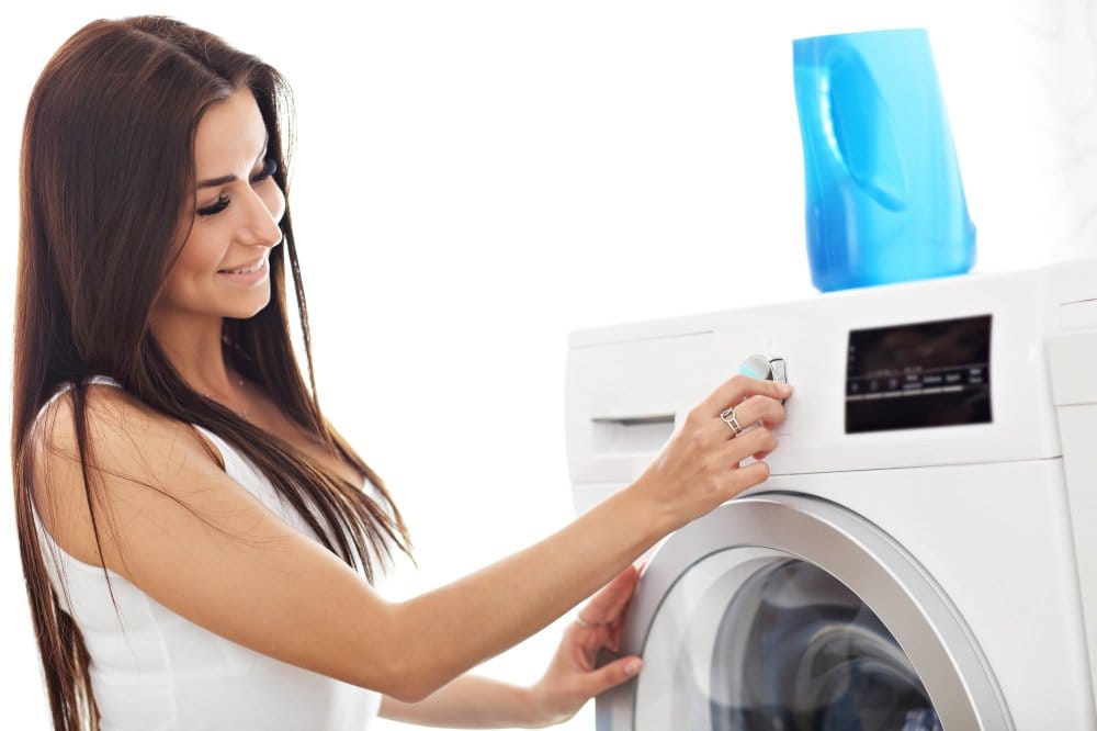 A woman adjusting the settings on a washing machine