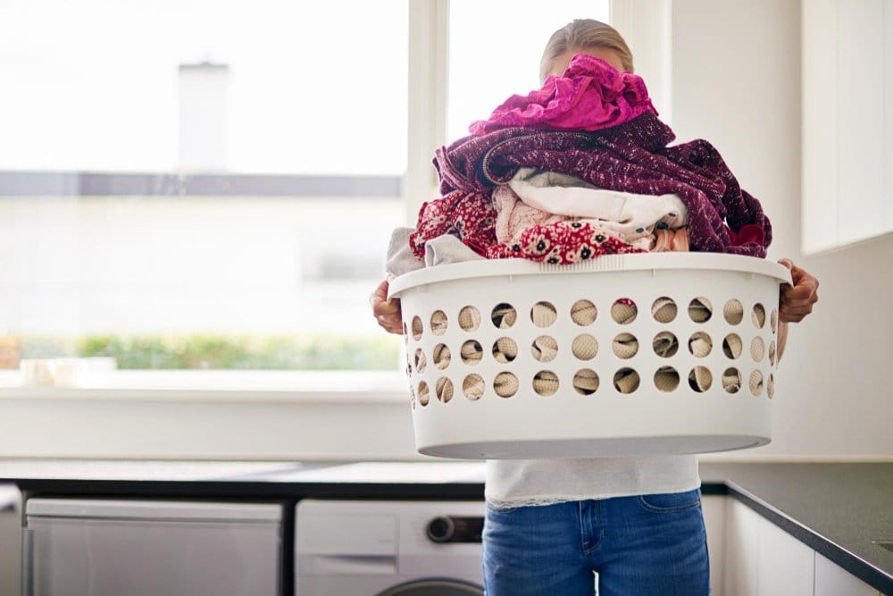 Cropped shot of young woman doing laundry at home