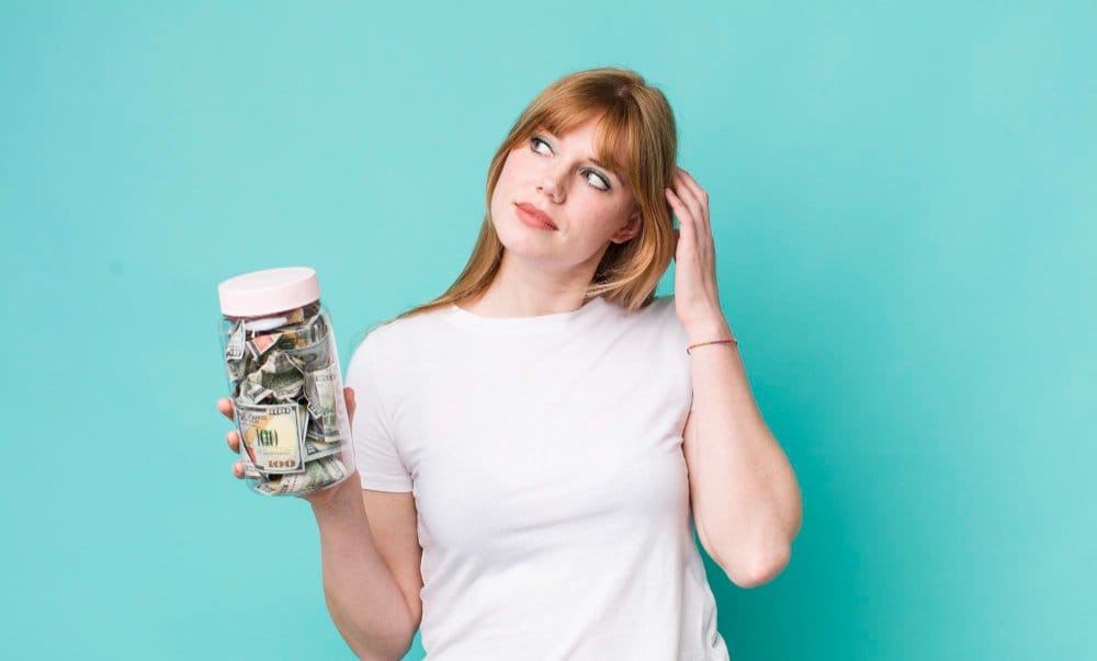 Woman holding jar of cash while thinking about profits from selling used clothes