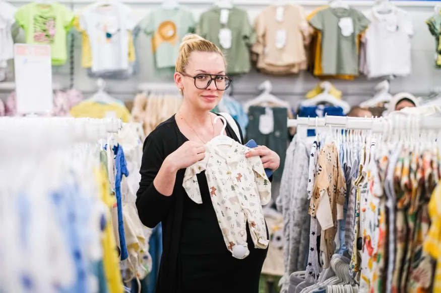 A colorful display of infant clothes in various sizes showing different age labels and sizing tags