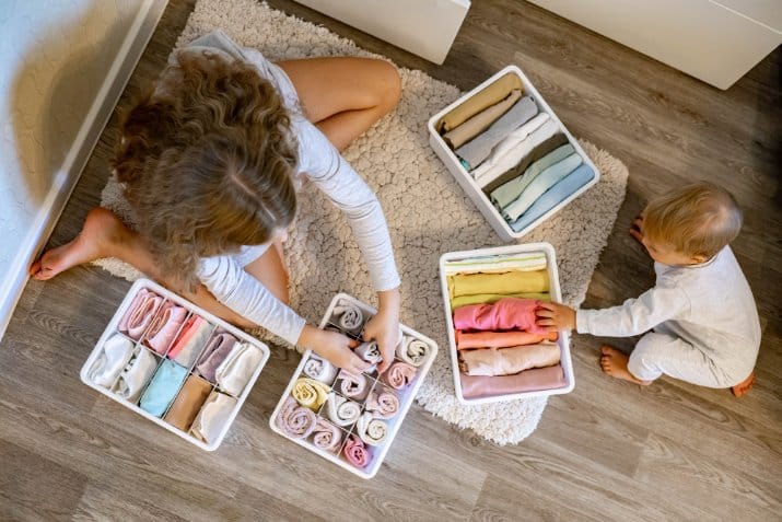 Little girl rolled up clothes using the marie kondo's method placing apparel in drawers