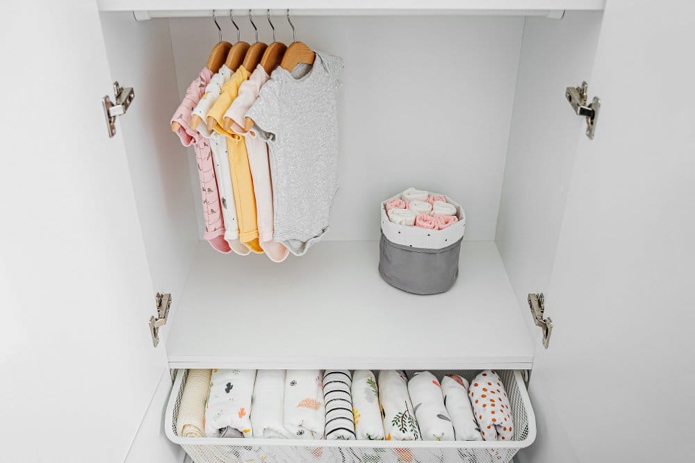 Set of baby bodysuits for a newborn girl and boy on hangers in white wardrobe