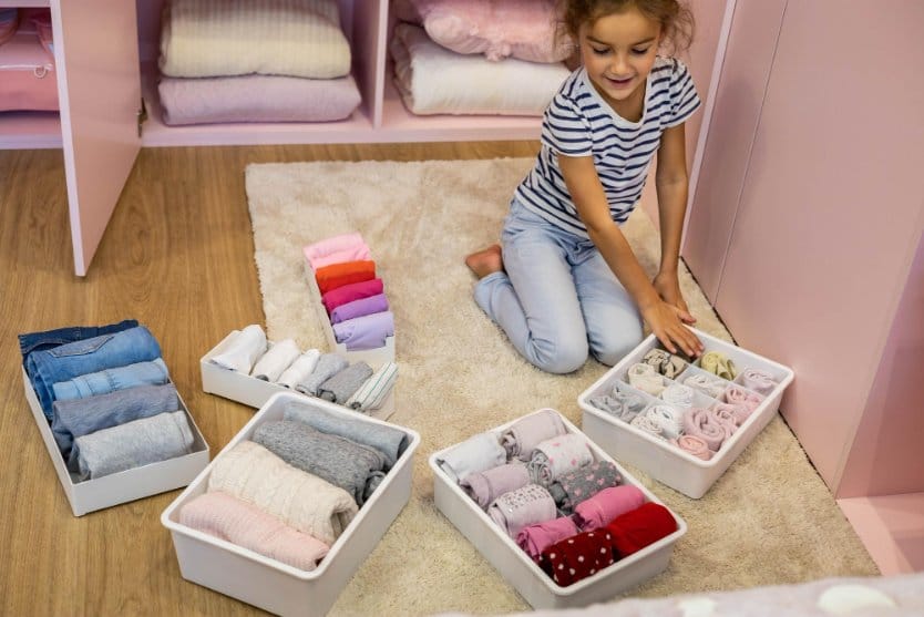 Little girl organizing clothes neatly in drawer compartments