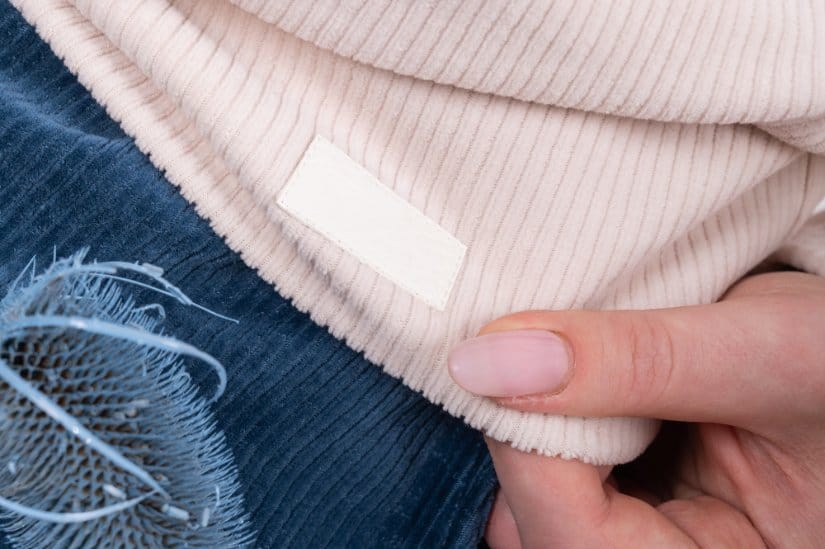 A woman demonstrating a spot on a clothe to add label or write toddler name