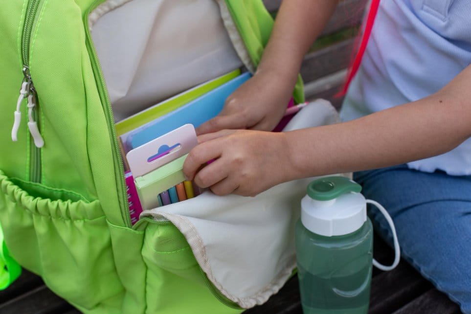 packing daycare supplies and water bottle in green backpack