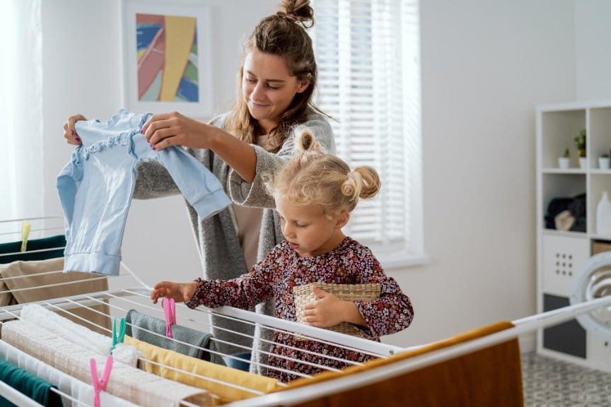 Mother and child hanging freshly washed toddler clothes to dry