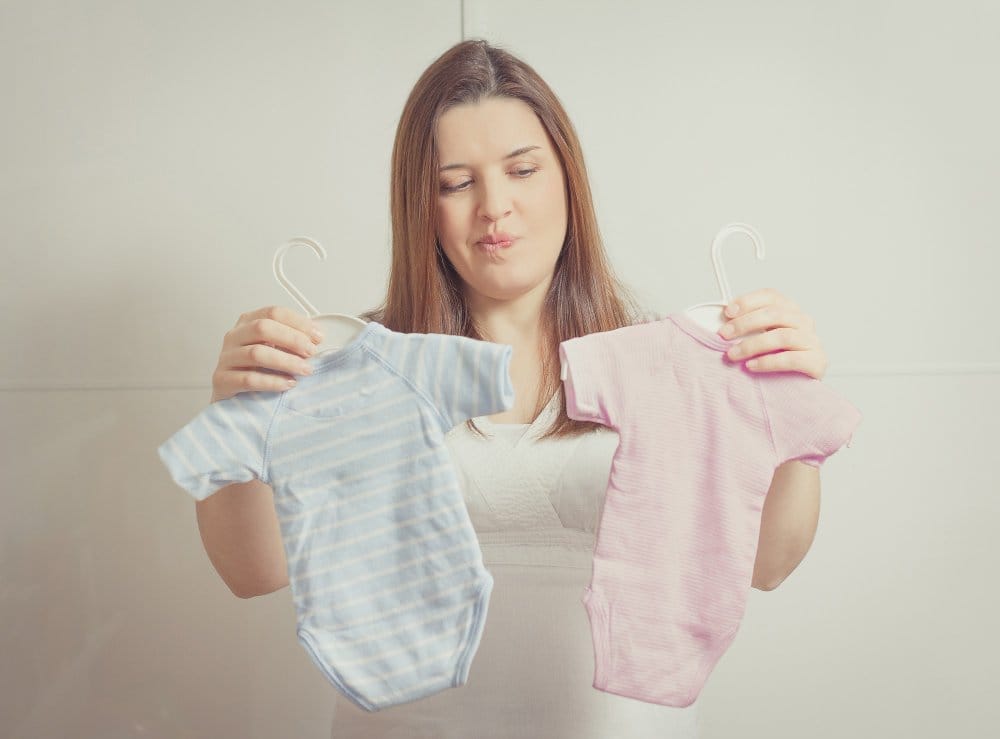 Parent comparing two baby outfits while deciding what to resell