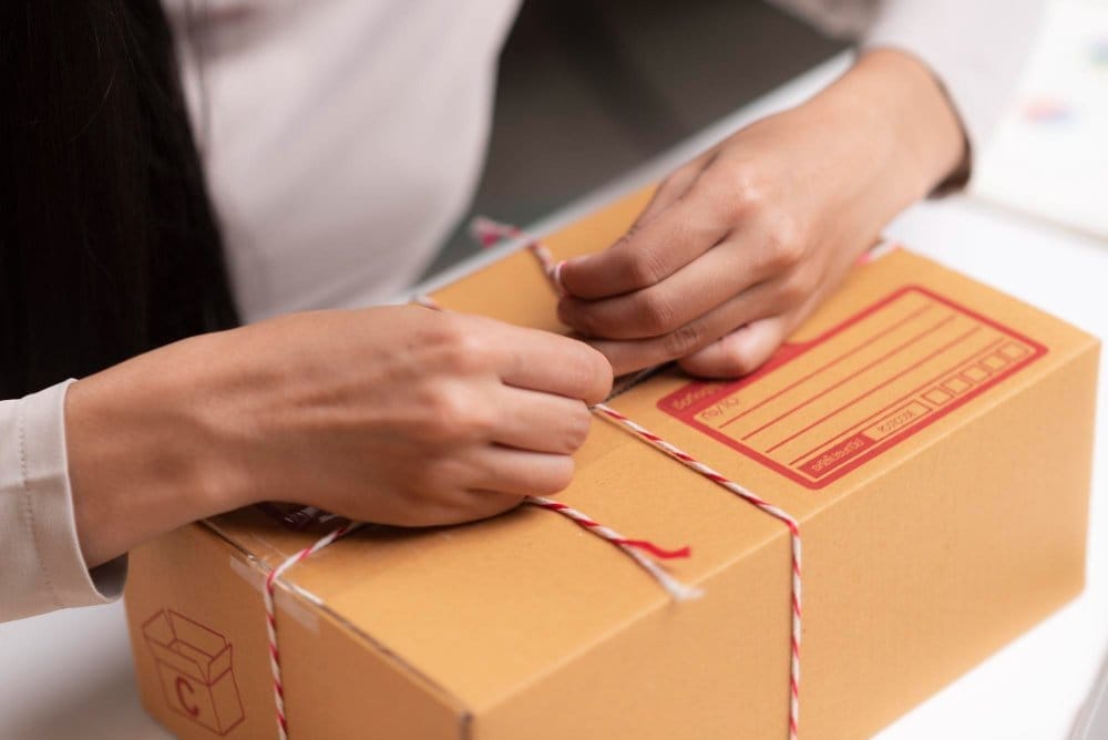 Hands tying string around a parcel ready to ship children's clothes sold online