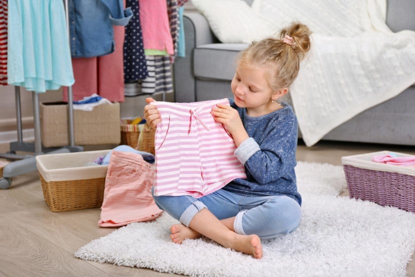 Little girl sitting on the floor checking out some clothes