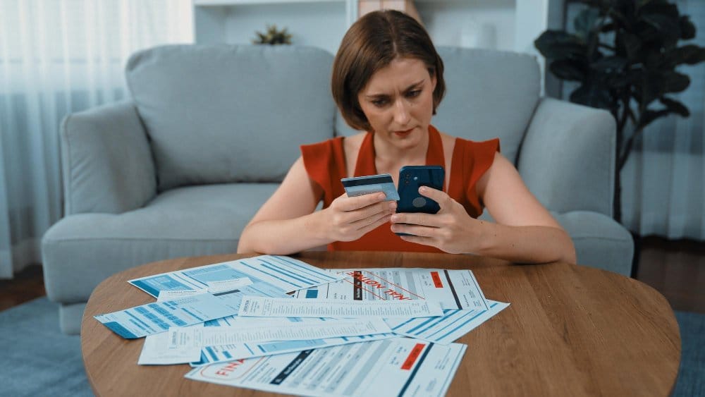 A woman holding a credit card and a phone making a payment online. ebay or vinted