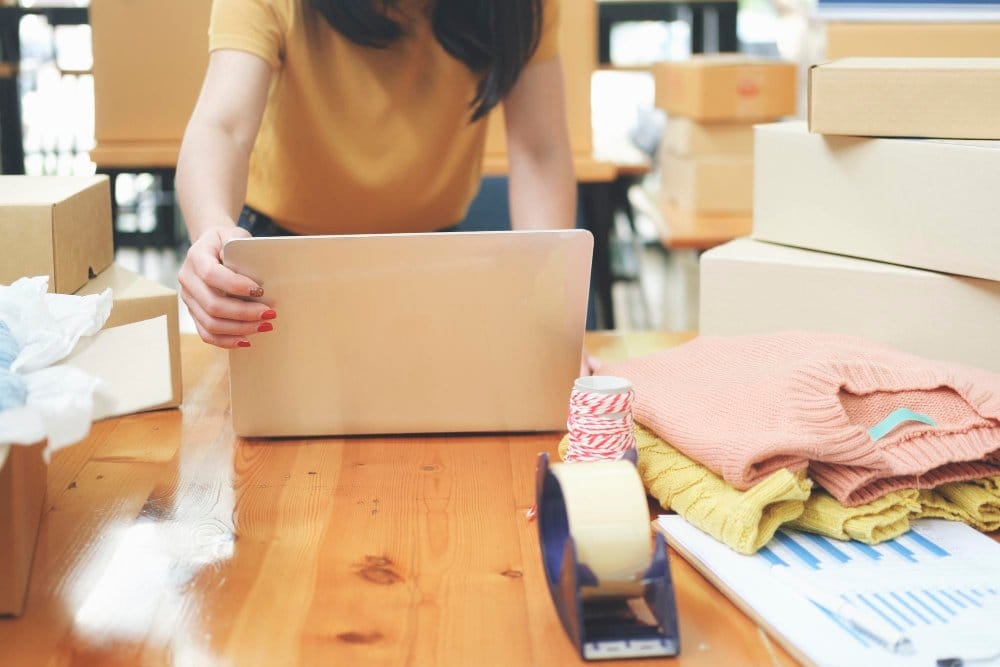 A woman using her laptop to list items for sale on eBay and Vinted