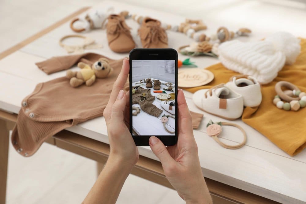 Woman taking picture of old toddler clothes to sell in online market place