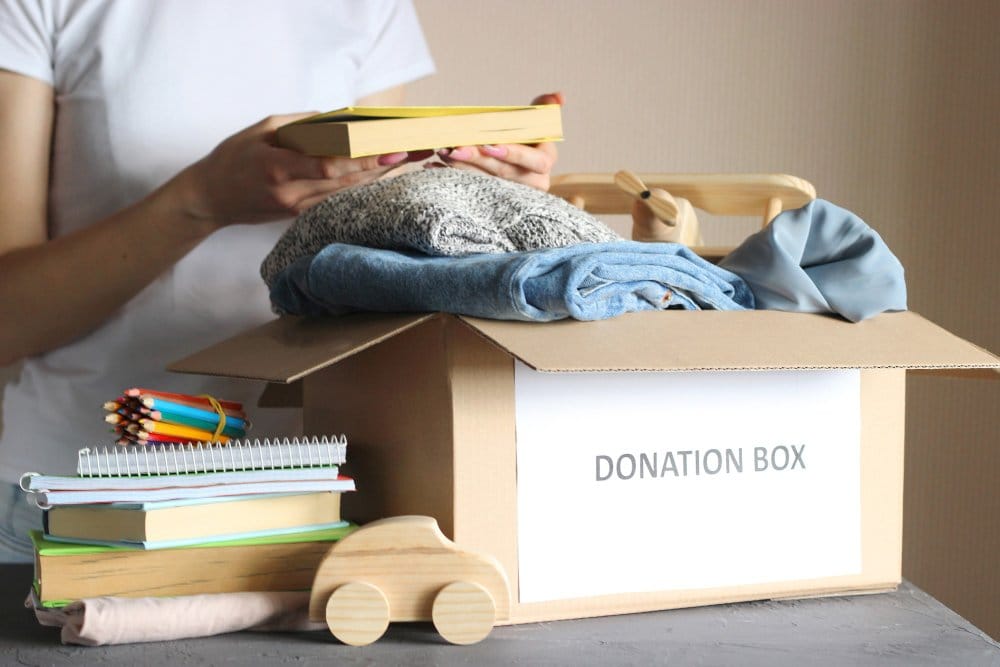 Girl puts various items in a box for donation