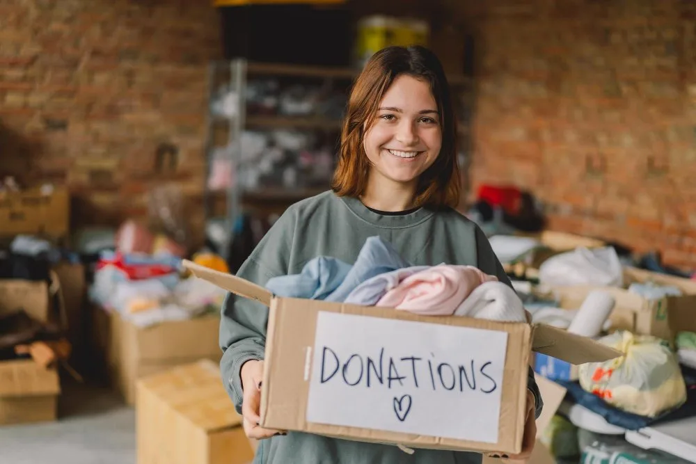 Volunteer teenage girl preparing donation boxes for people