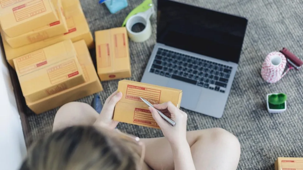 Young woman is writing down the customers details and addresses on the shipping box