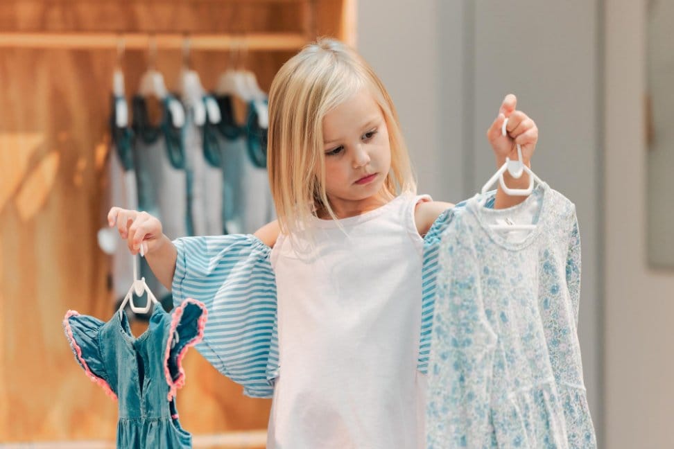 Little girl looking at various clothes in different brands