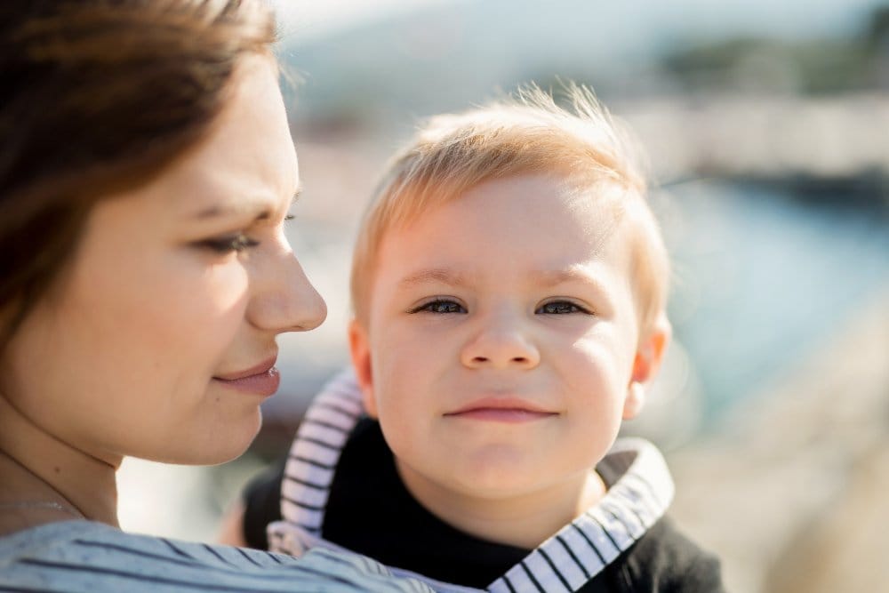 Mother holding toddler outdoors showing close up of child skin