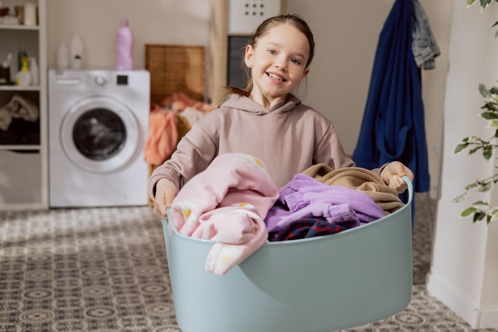A little girl carry a containing full of laundry