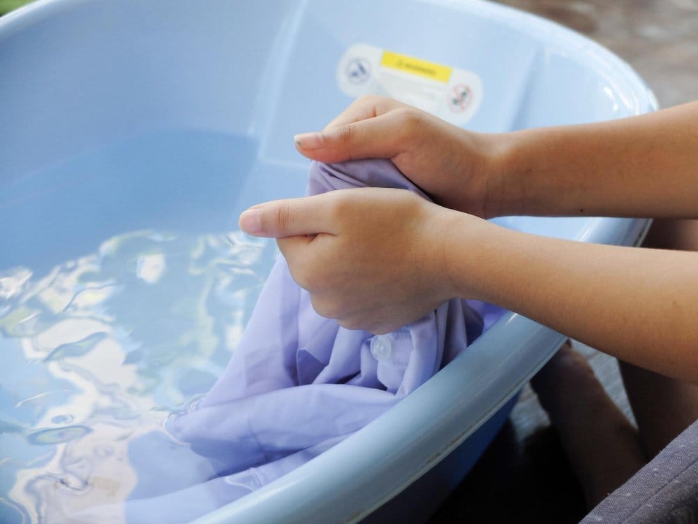 A view of someone hand washing toddler clothes