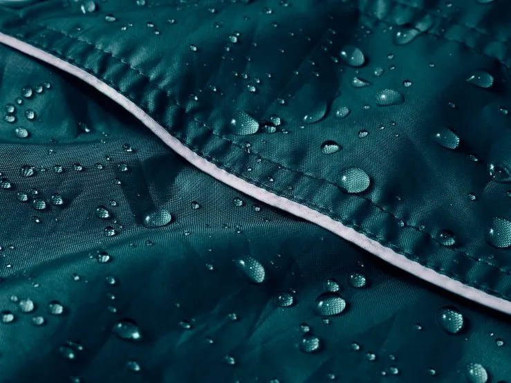 Close up of treated jacket fabric with seam detail and water droplets, example of DWR application