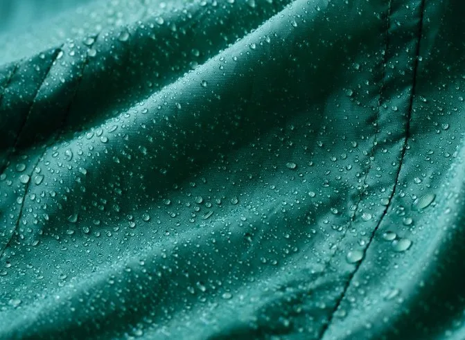 Green outdoor fabric with water droplets beading on surface, showing advantages of DWR protection