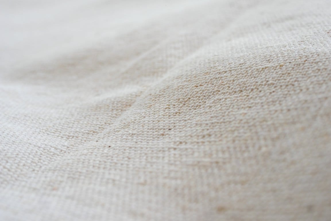 Various types of organic cotton fabrics displayed showing different weaves and textures suitable for baby clothing