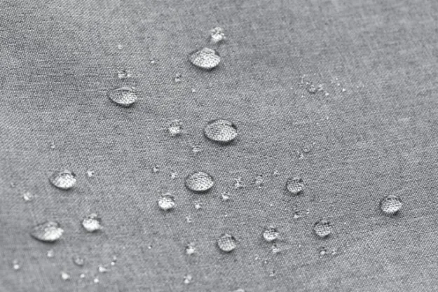 Water droplets on light gray fabric after retreatment, demonstrating restored DWR performance