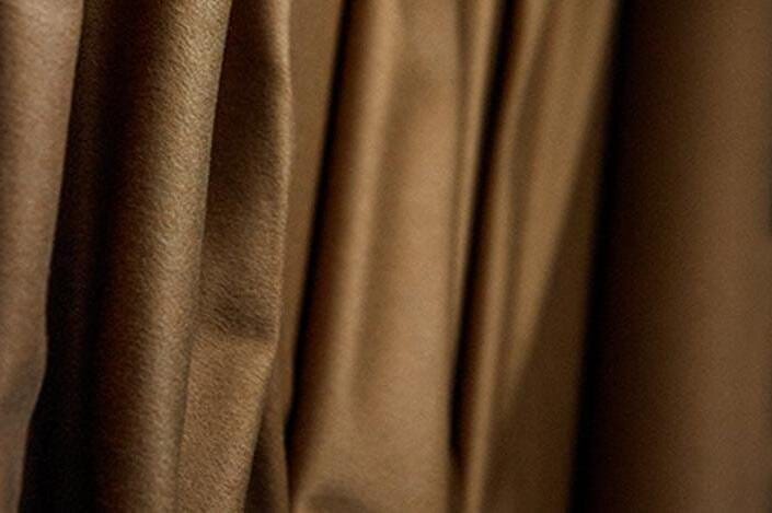 Rich brown luxury fabric with smooth elegant folds representing rare textiles