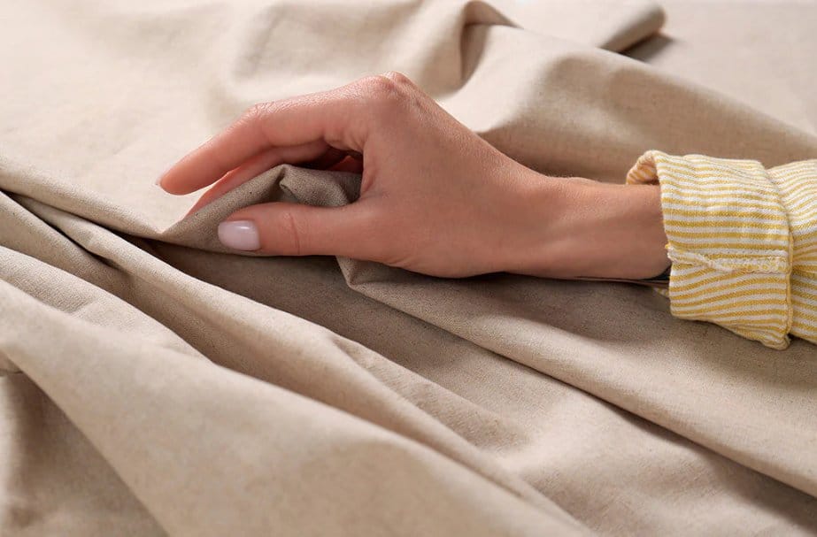 Hand touching soft beige fabric to test texture and comfort for sensitive skin