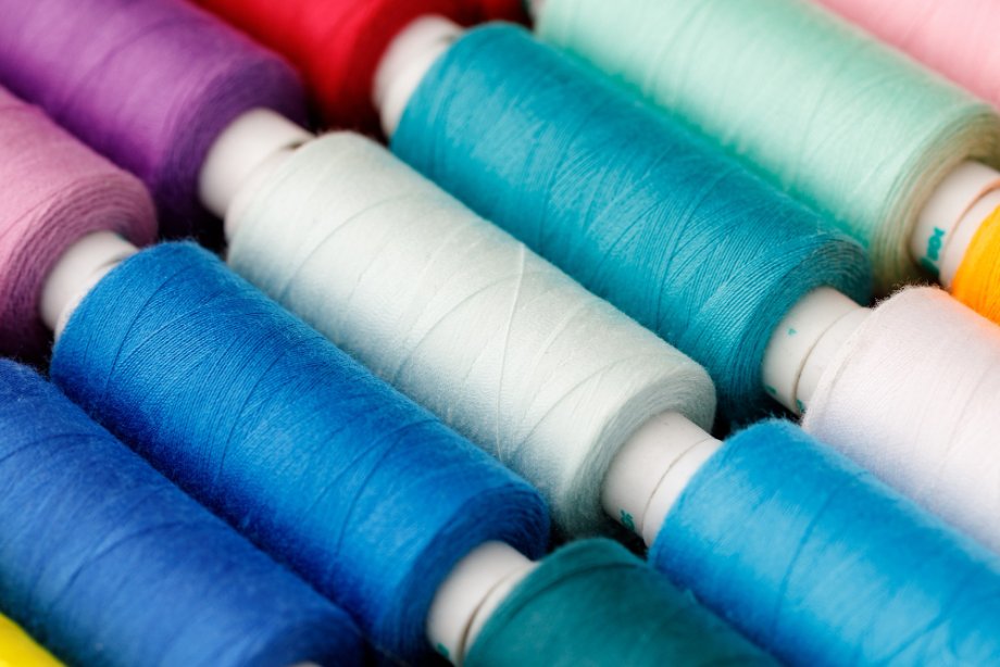 Close-up of spools of sewing thread in vibrant colors including blue, turquoise, red, and pink.