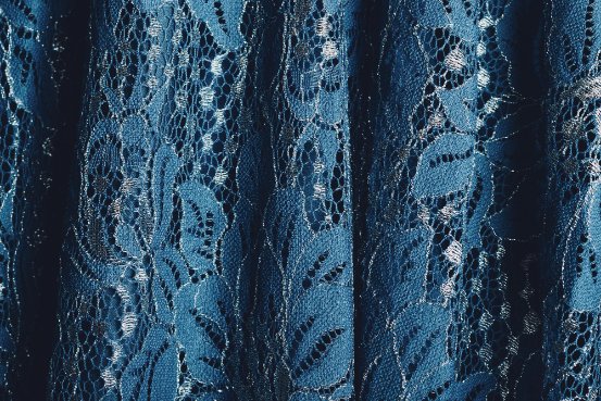 Close-up of Raschel lace fabric showing intricate floral patterns and mesh structure