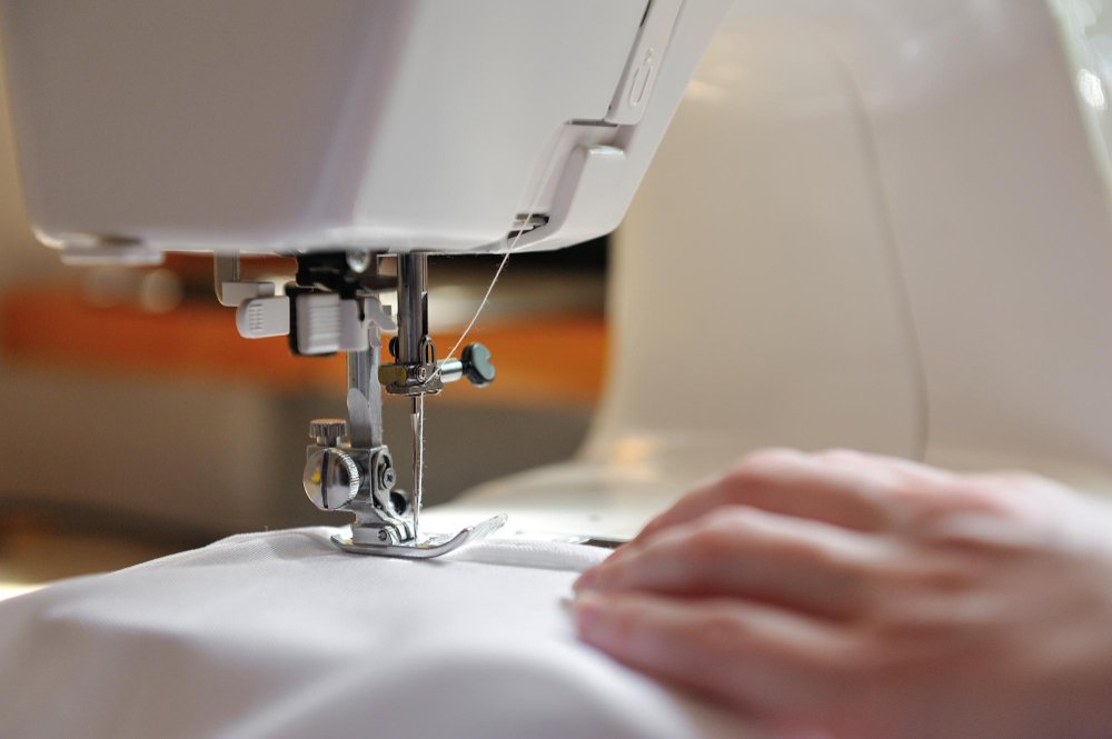Close-up of sewing machine needle stitching white fabric, in reference to bound seams