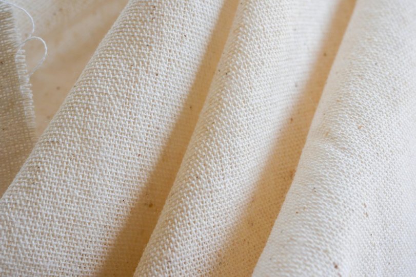 Close-up of natural beige canvas cotton fabric with visible texture and weave.