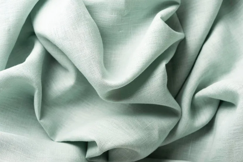 Close-up of mint green cotton lawn fabric with soft folds.
