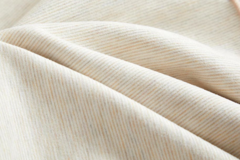 Beige cotton twill fabric with soft folds and diagonal weave.