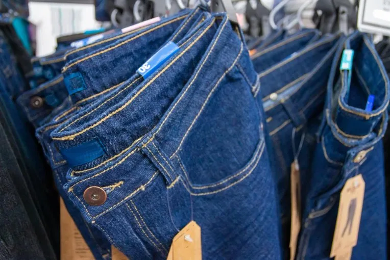 Visual buying guide showing different quality indicators in denim including fabric weight, stitching quality, and construction details