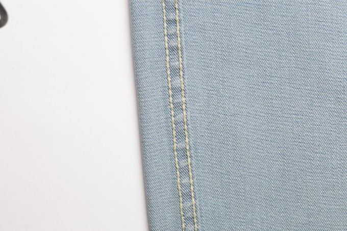 Close-up of double-stitched flat-fell seam on light blue denim fabric.