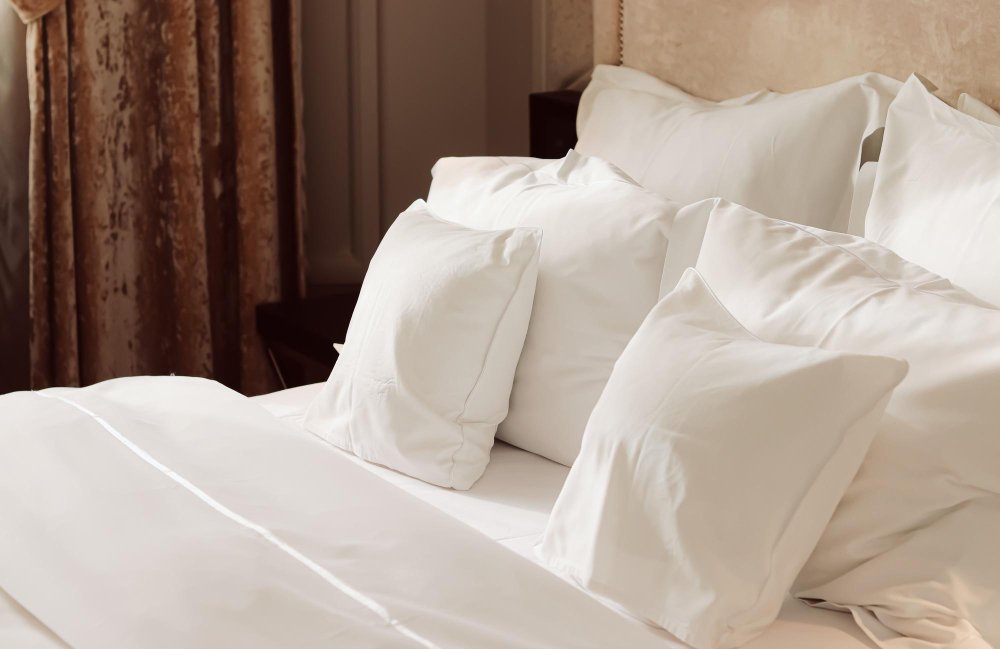 Luxury hotel bedroom setup showing crisp white sateen sheets and elegant bedding arrangement