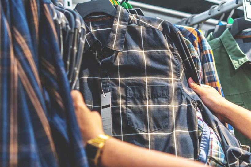 Person examining flannel fabric quality, checking texture and weight while shopping for textiles